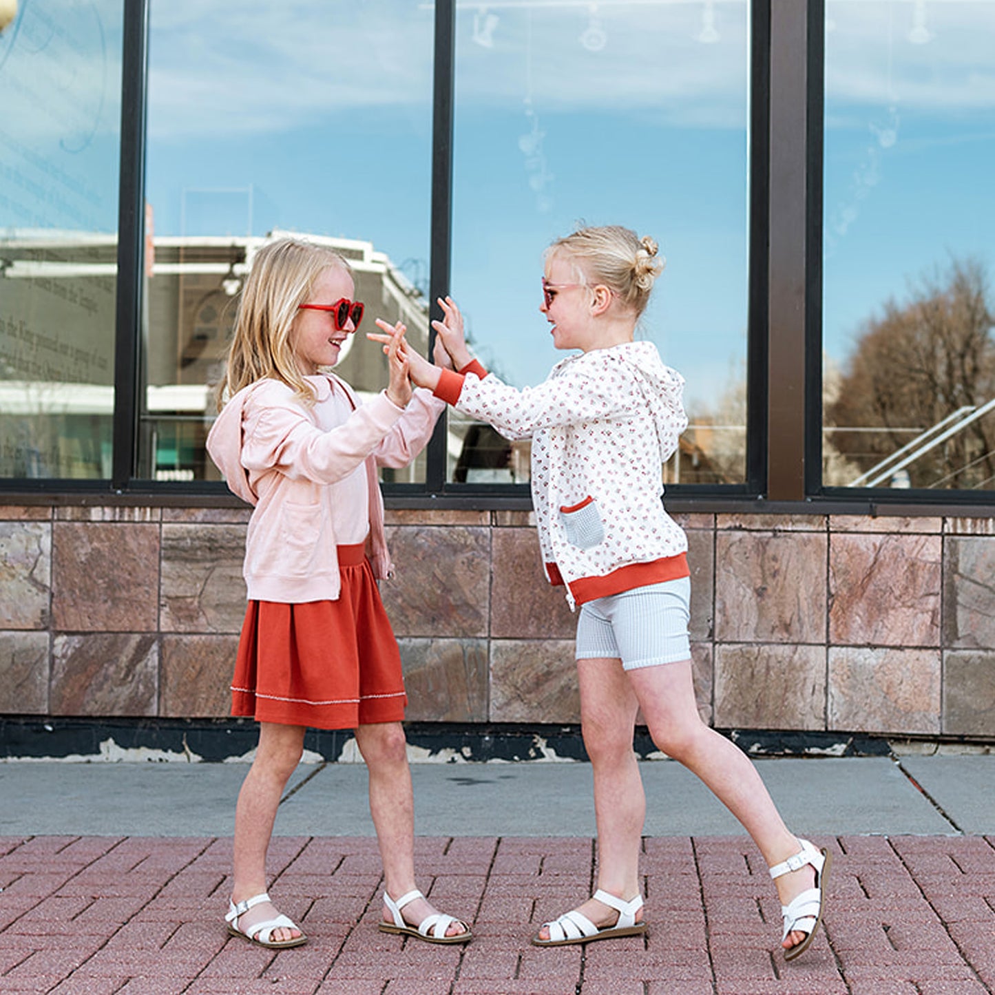 two little girls playing patty cake on the sidewalk wearing high quality ethically made organic pima cotton kids clothing styles.